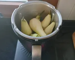 Step <p>Pon en el vaso el agua, el vino, el amaretto(opcional), el azúcar, el anís estrellado, la vainilla y las peras e inicia Sin tapa/30 min/100°C. Es importante que de vez en cuando las remuevas con la espátula para que las que quedan por arriba bajen y se cocinen también. Con ayuda de 2 cucharas o unas pinzas, retira las peras y colócalas en un plato. Cuela el contenido del vaso en una jarra y reserva.</p> illustration