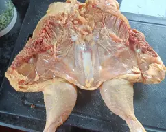 Step <p>Con unas tijeras fuertes, corte a ambos lados de la columna vertebral del pollo y retírela. Abra el pollo y dele la vuelta para que las pechugas queden hacia arriba y presione fuertemente las pechugas y muslos para que el pollo quede plano. Espolvoree el pollo por ambos lados con 1 cucharadita de sal, 2-3 pellizcos de pimienta y el pimentón y colóquelo, con la piel hacia abajo, en el recipiente Varoma. Tape el Varoma y reserve.</p> illustration